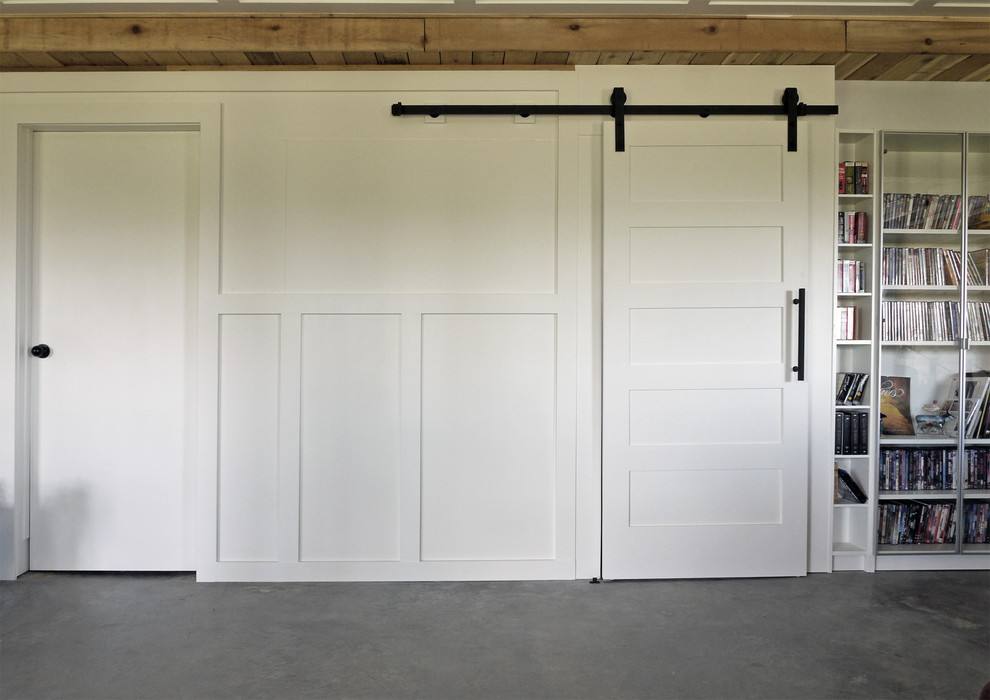 Ejemplo de sótano con puerta industrial pequeño con paredes blancas, suelo de cemento y suelo gris