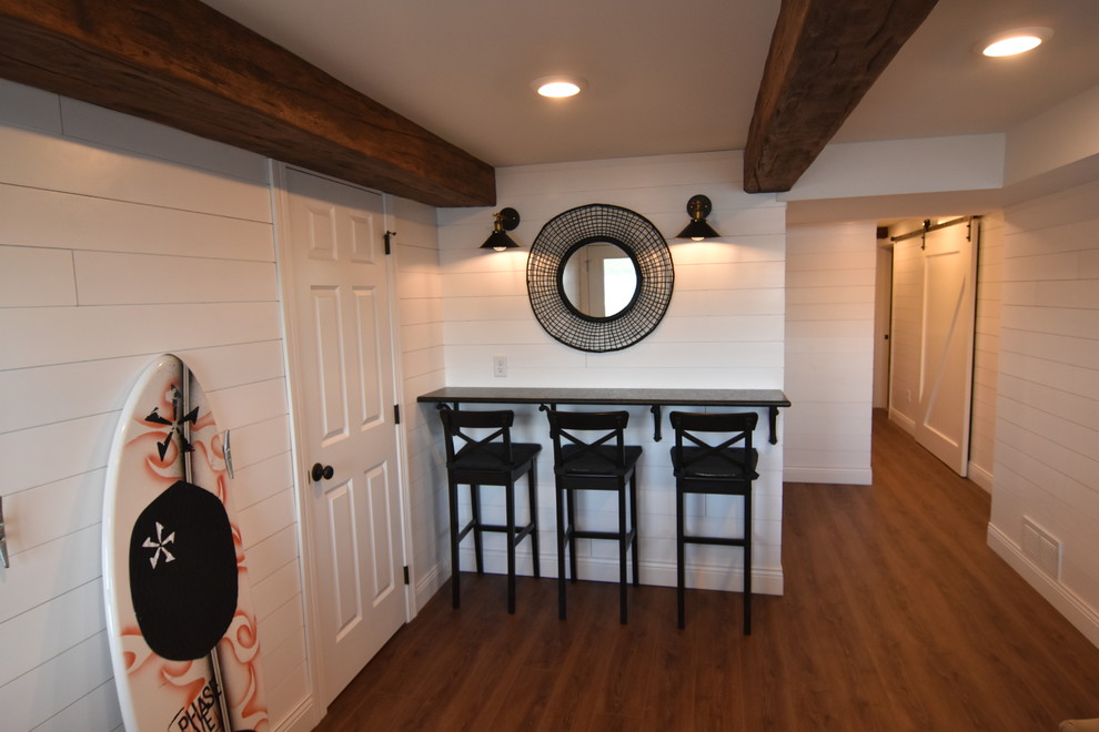 Example of a small beach style walk-out vinyl floor and brown floor basement design in Other with white walls
