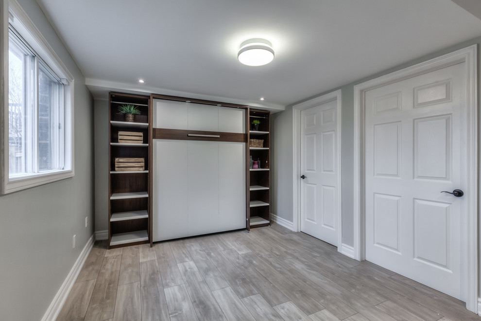 Small nautical walk-out basement in Toronto with white walls and laminate floors.