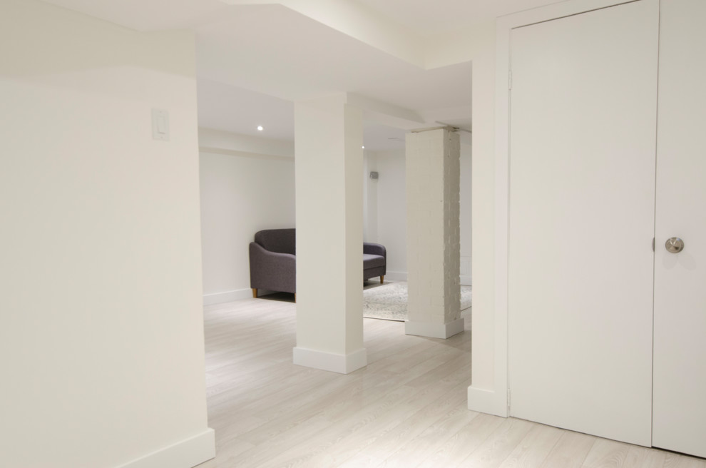 Diseño de sótano con ventanas clásico renovado de tamaño medio con paredes blancas, suelo laminado y suelo beige