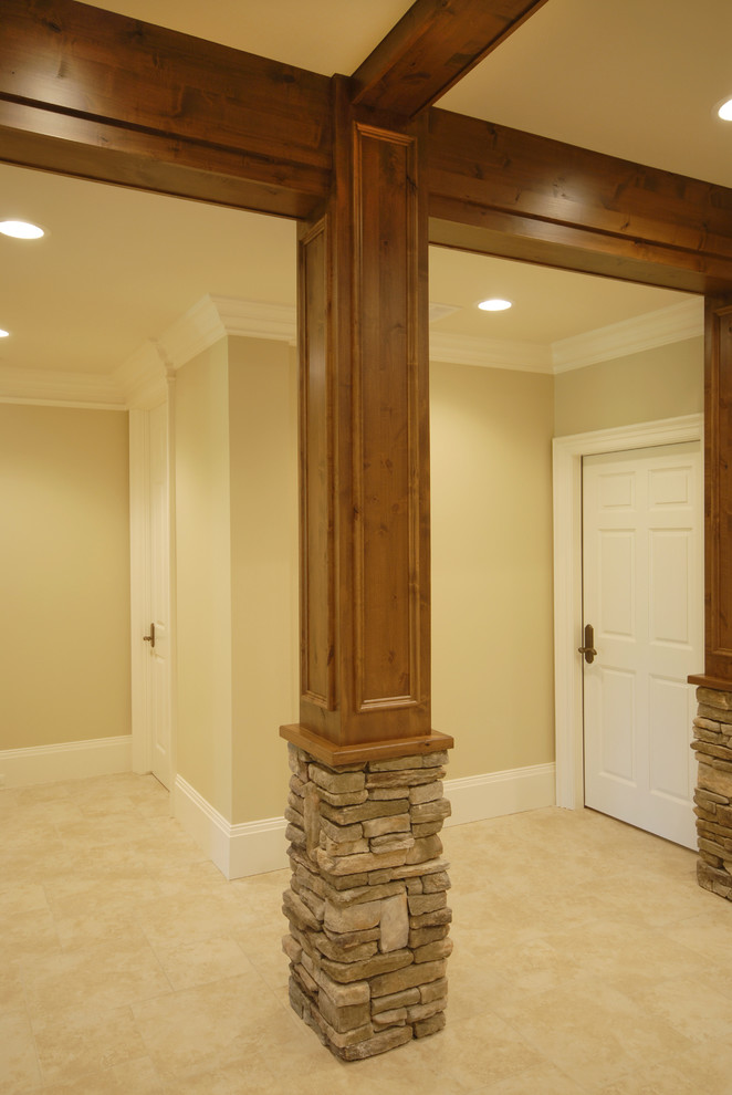 Réalisation d'un grand sous-sol chalet avec un mur beige, moquette, une cheminée double-face, un manteau de cheminée en pierre et un sol beige.