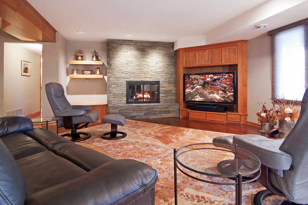 This is an example of a classic look-out basement in Minneapolis with grey walls, dark hardwood flooring, a standard fireplace, a stone fireplace surround and a chimney breast.