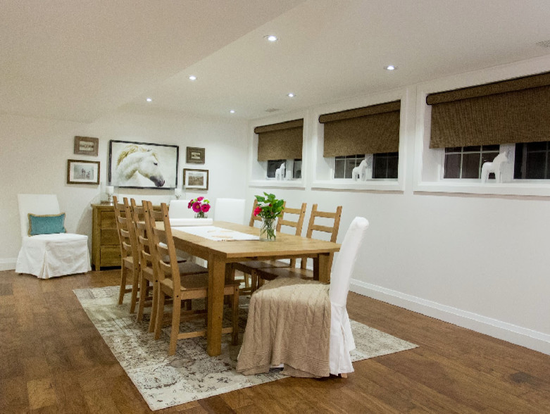 Exemple d'une grande salle à manger tendance avec un mur blanc, parquet clair, une cheminée standard et un manteau de cheminée en pierre.