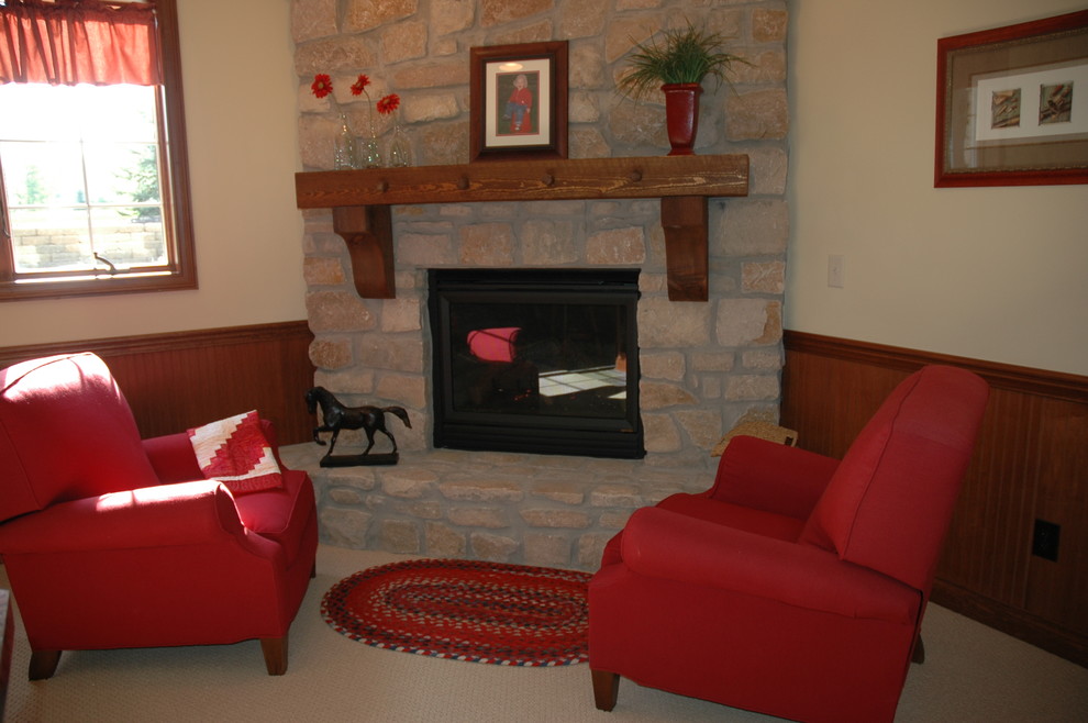 Elegant look-out carpeted basement photo in Indianapolis with beige walls, a standard fireplace and a stone fireplace
