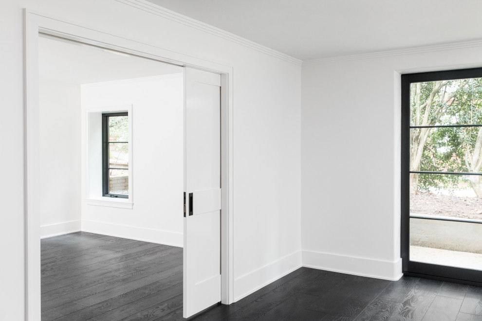 Cette photo montre un sous-sol chic donnant sur l'extérieur et de taille moyenne avec un mur blanc, un sol en vinyl et un sol noir.