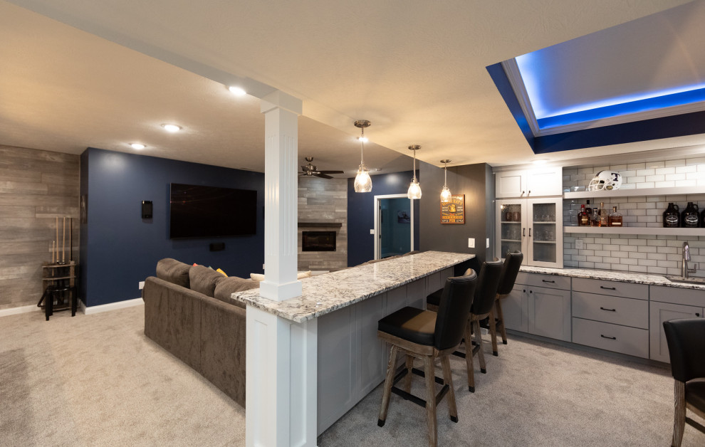 Idées déco pour un grand sous-sol contemporain avec un mur bleu, moquette, une cheminée standard, un manteau de cheminée en carrelage et un sol beige.