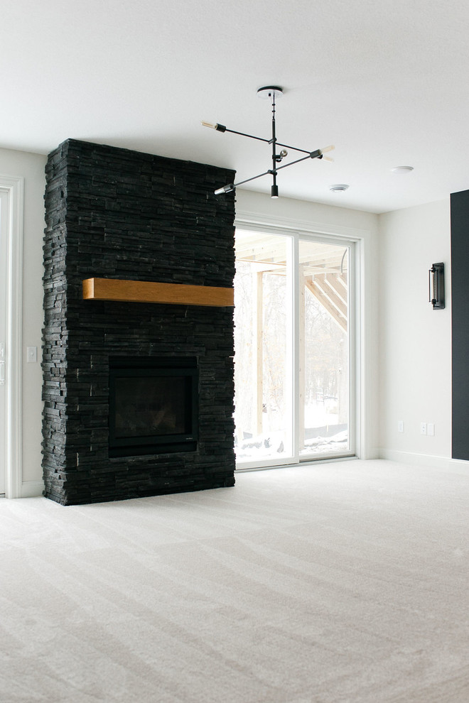 Idée de décoration pour un grand sous-sol minimaliste donnant sur l'extérieur avec un mur blanc, moquette, une cheminée standard, un manteau de cheminée en pierre et un sol blanc.