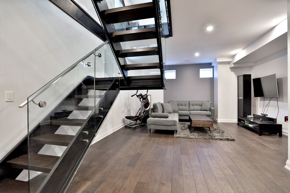 Medium sized modern look-out basement with grey walls and dark hardwood flooring.
