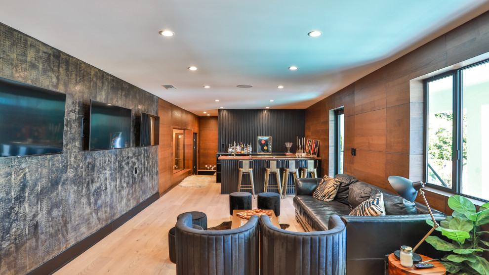 Design ideas for an expansive modern walk-out basement in Los Angeles with a home bar and black walls.