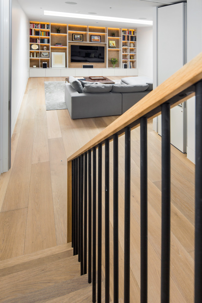 Photo of an expansive traditional fully buried basement in London with white walls, medium hardwood flooring and brown floors.