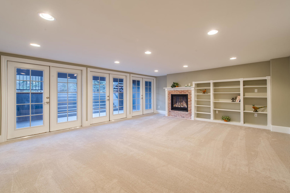 Transitional walk-out carpeted basement photo in Denver with gray walls, a standard fireplace and a brick fireplace