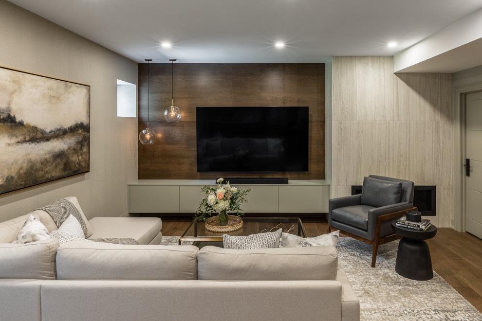 Design ideas for a medium sized traditional walk-out basement in Toronto with a home bar, beige walls, medium hardwood flooring, a ribbon fireplace, a tiled fireplace surround, brown floors and wood walls.