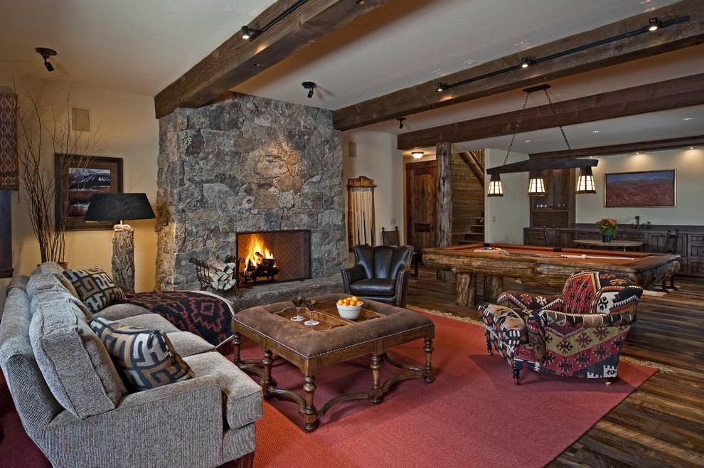 Example of a mountain style dark wood floor and brown floor living room design in Denver with a stone fireplace, a standard fireplace and beige walls