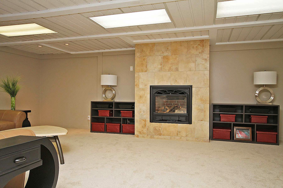 Cette image montre un grand sous-sol traditionnel avec un mur beige, moquette, une cheminée standard et un manteau de cheminée en carrelage.