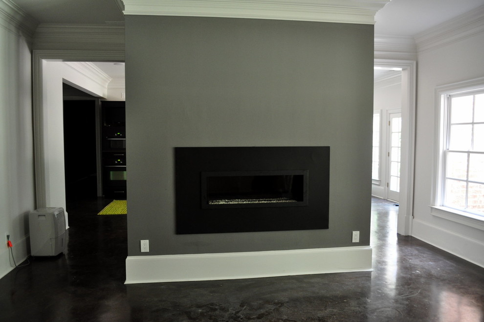 Inspiration pour un grand sous-sol design avec un mur gris, une cheminée standard et un sol noir.