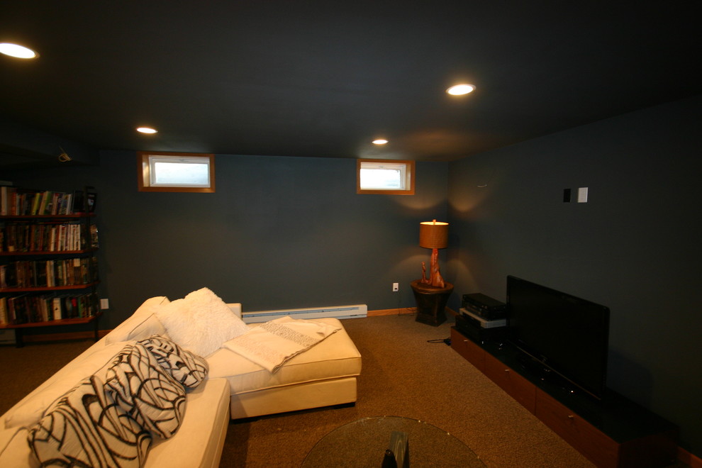 Foto på en mellanstor funkis källare utan fönster, med svarta väggar, heltäckningsmatta, en standard öppen spis och en spiselkrans i tegelsten