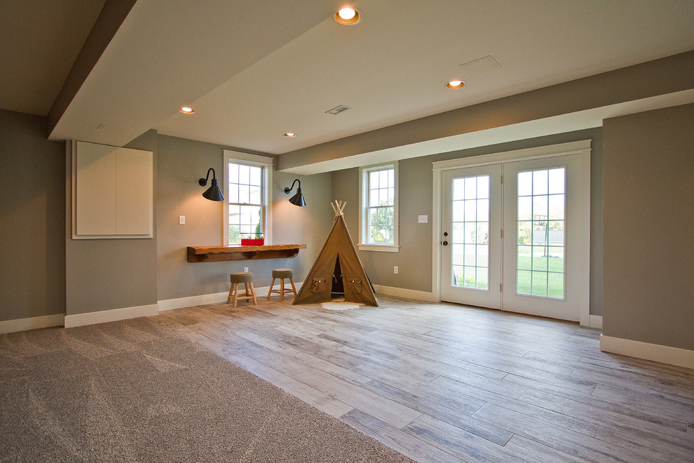Diseño de sótano con ventanas de estilo americano grande sin chimenea con paredes beige, suelo de madera clara y suelo marrón