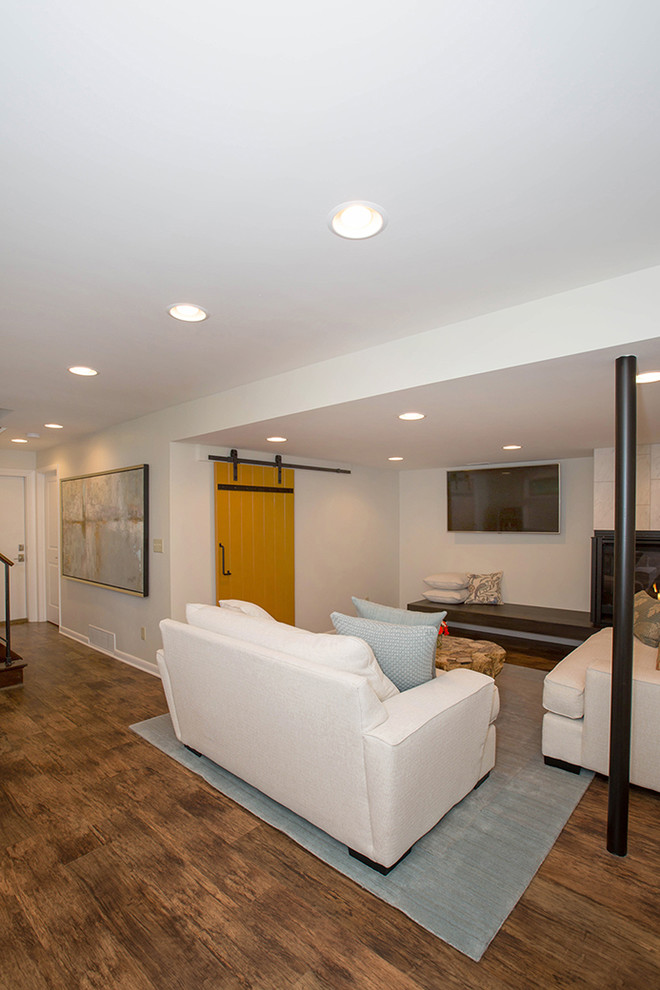 Mittelgroßes Modernes Untergeschoss mit beiger Wandfarbe, braunem Holzboden, Eckkamin, gefliester Kaminumrandung und braunem Boden in Cincinnati