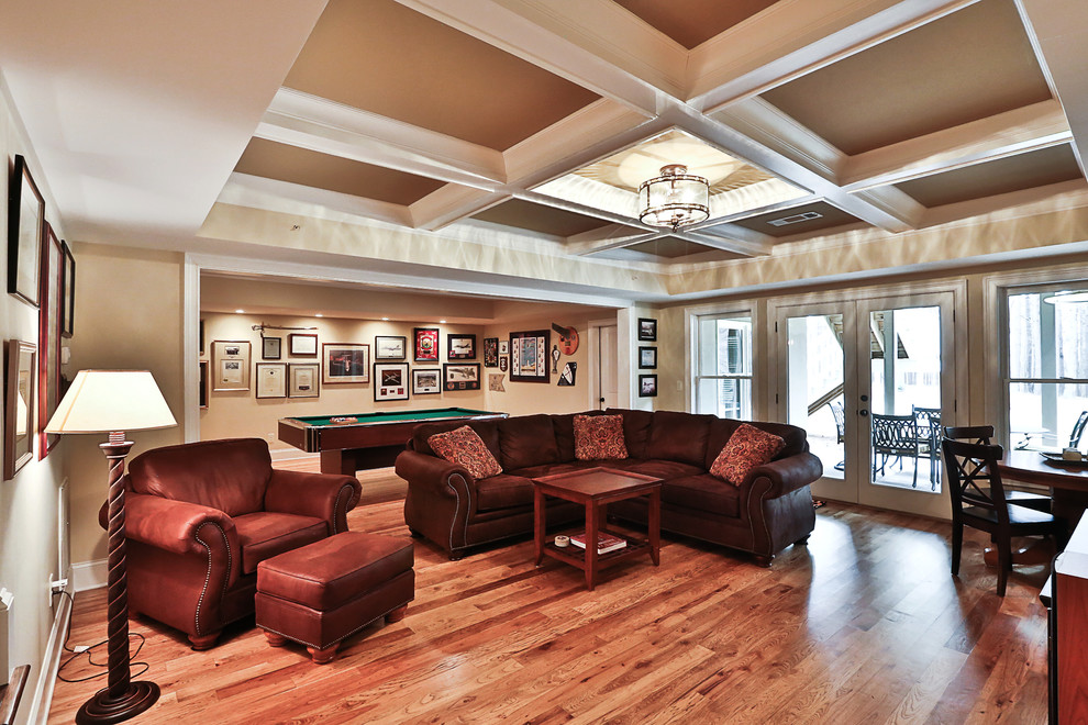 This is an example of a large traditional walk-out basement in Atlanta with beige walls, medium hardwood flooring and no fireplace.
