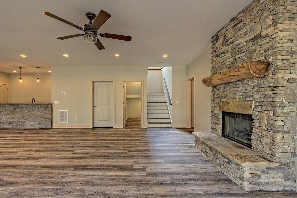 Inspiration for a large craftsman walk-out vinyl floor and brown floor basement remodel in Atlanta with beige walls, a two-sided fireplace and a stone fireplace