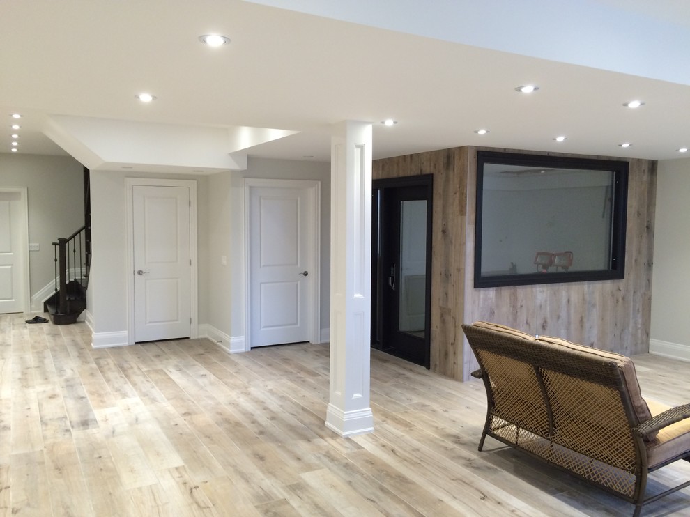 Large traditional fully buried basement in Toronto with grey walls, light hardwood flooring, no fireplace and beige floors.