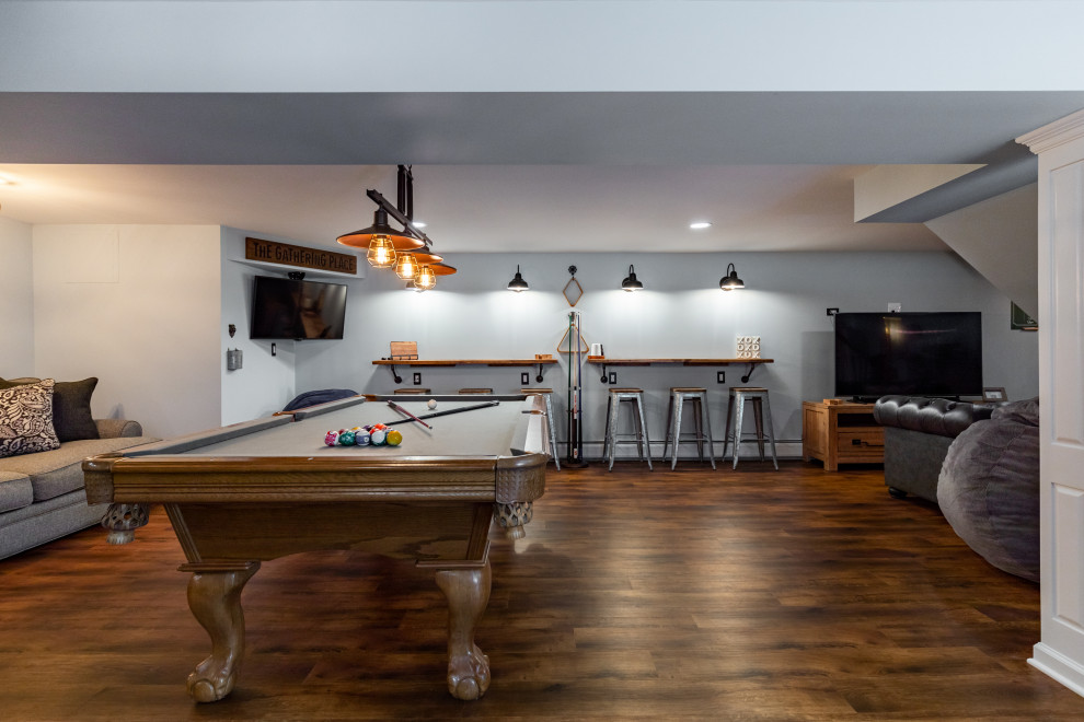 Photo of a large traditional walk-out basement in New York with a game room, grey walls, dark hardwood flooring and brown floors.