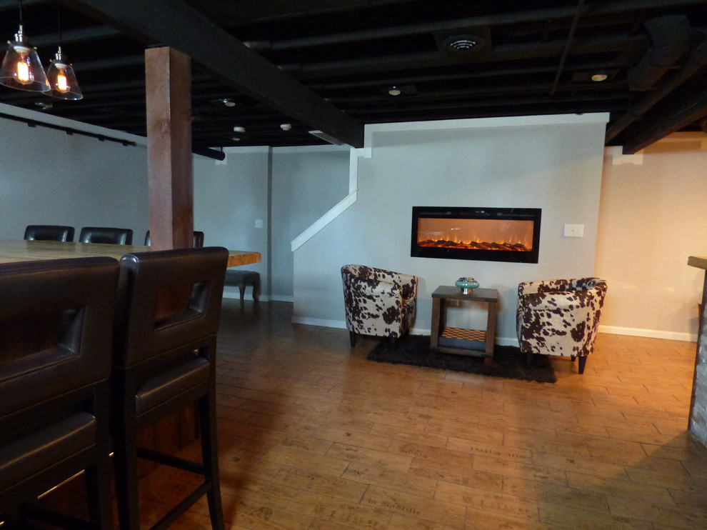 Immagine di una taverna stile americano interrata di medie dimensioni con pareti grigie, pavimento con piastrelle in ceramica e camino lineare Ribbon