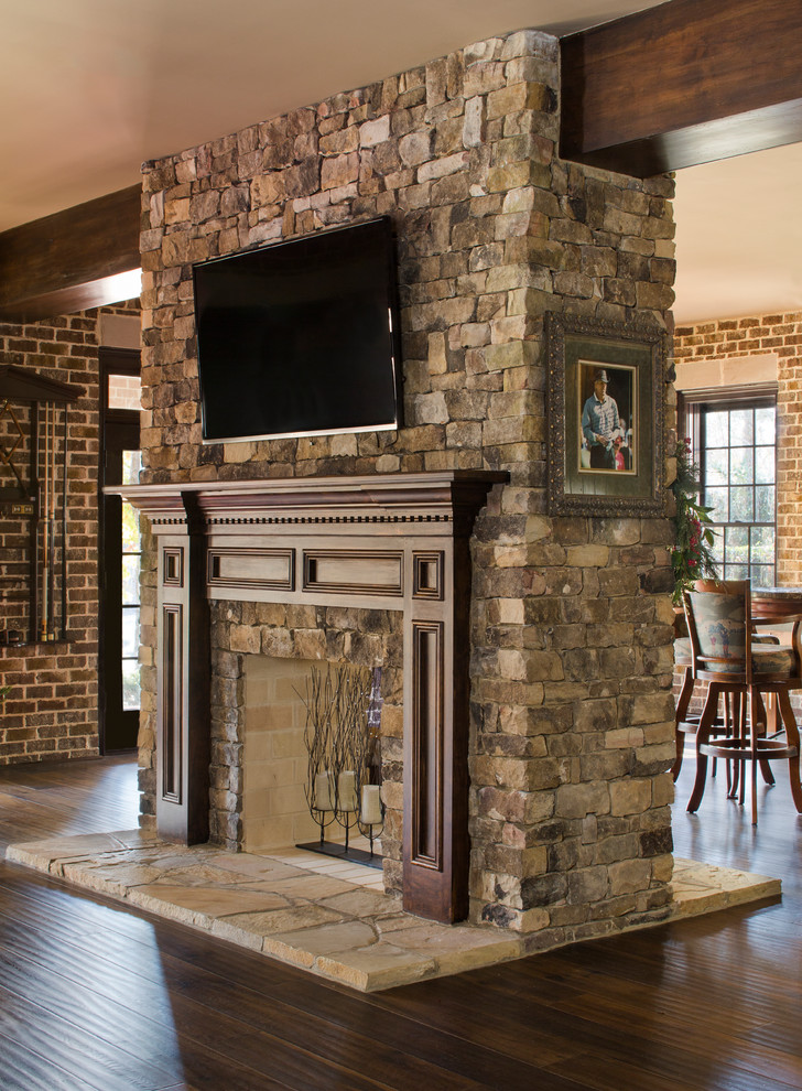 Cette photo montre un grand sous-sol donnant sur l'extérieur avec un mur marron, parquet foncé, une cheminée standard et un manteau de cheminée en pierre.