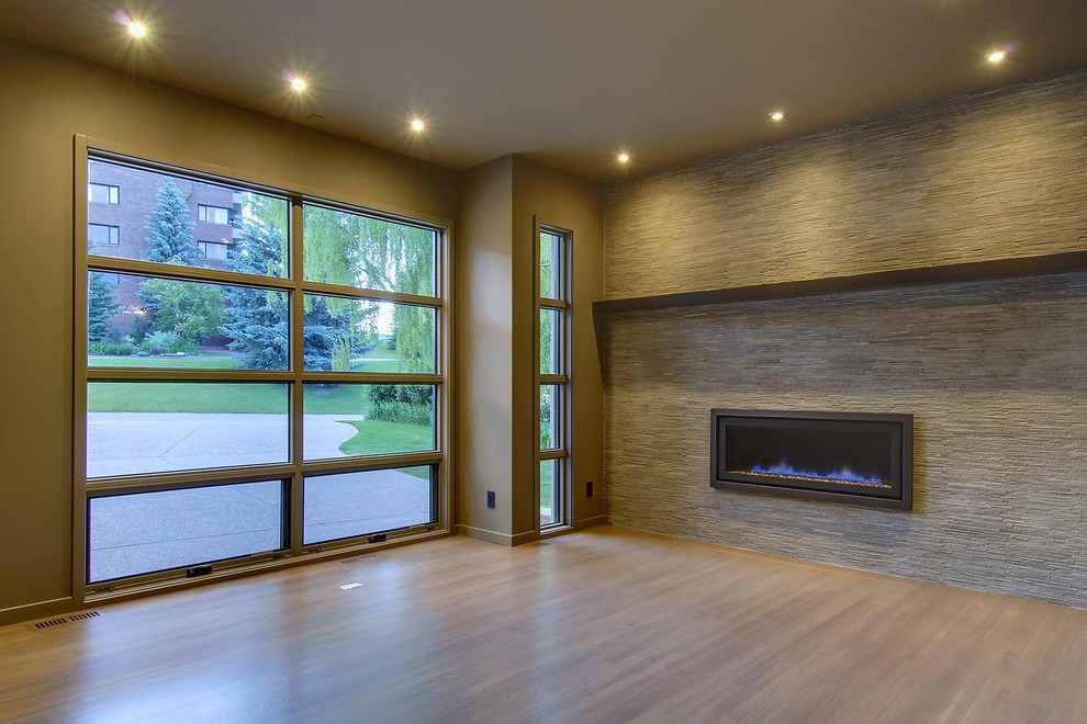 Basement - mid-sized contemporary light wood floor basement idea in Calgary with gray walls, a ribbon fireplace and a stone fireplace