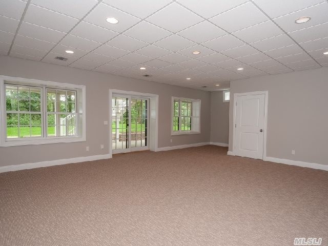 Large classic walk-out basement in New York with white walls, carpet, no fireplace and beige floors.