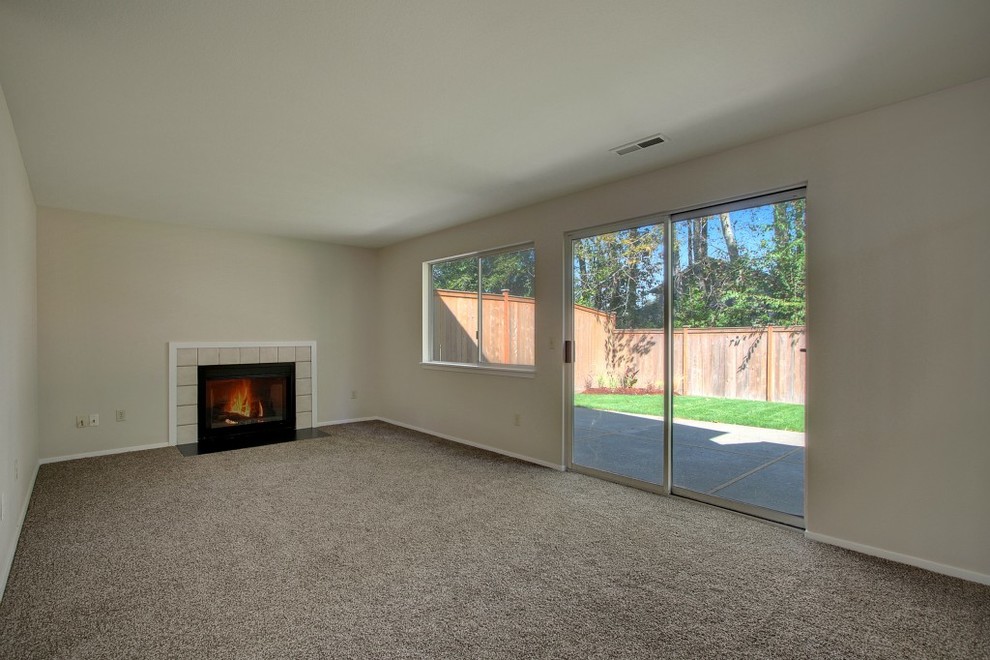 Inspiration for a mid-sized timeless walk-out carpeted basement remodel in Seattle with beige walls, a standard fireplace and a tile fireplace