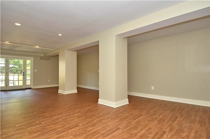 Photo of a large traditional walk-out basement in DC Metro with beige walls, medium hardwood flooring and brown floors.