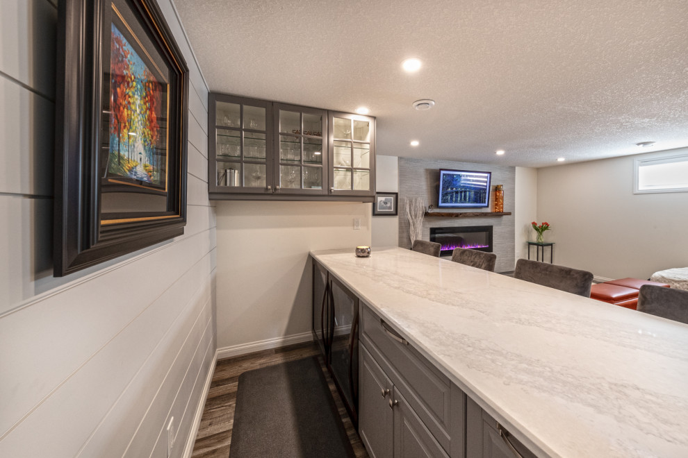 Basement - mid-sized modern underground vinyl floor, brown floor and shiplap wall basement idea in Edmonton with a bar, white walls, a standard fireplace and a tile fireplace