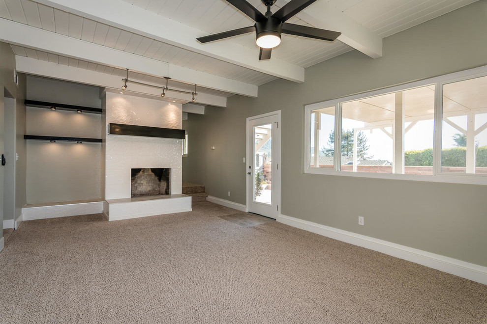 Inspiration for a medium sized contemporary walk-out basement in San Luis Obispo with grey walls, carpet, a standard fireplace, a tiled fireplace surround and beige floors.