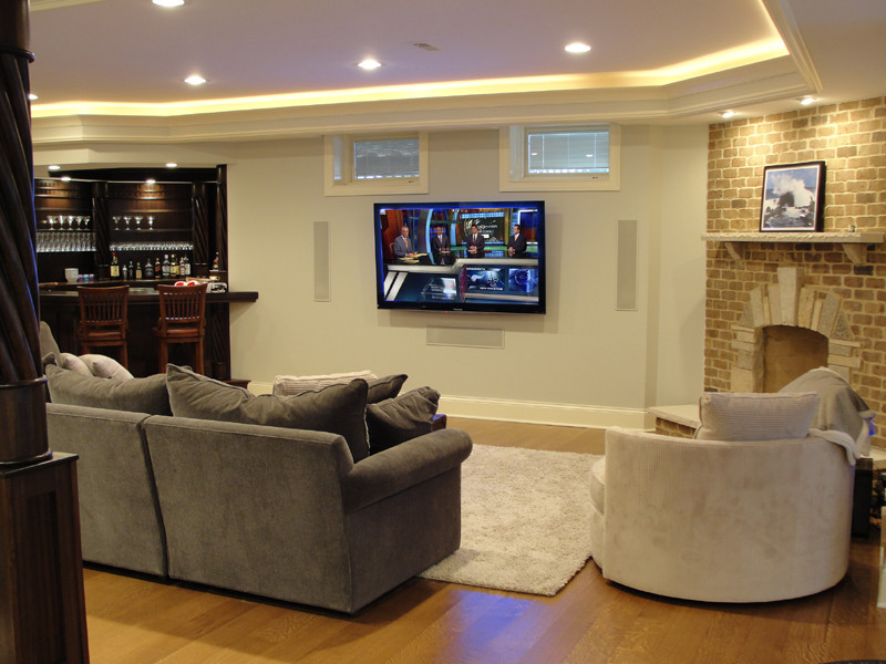 Large traditional look-out basement in Chicago with white walls, light hardwood flooring, a standard fireplace and a brick fireplace surround.