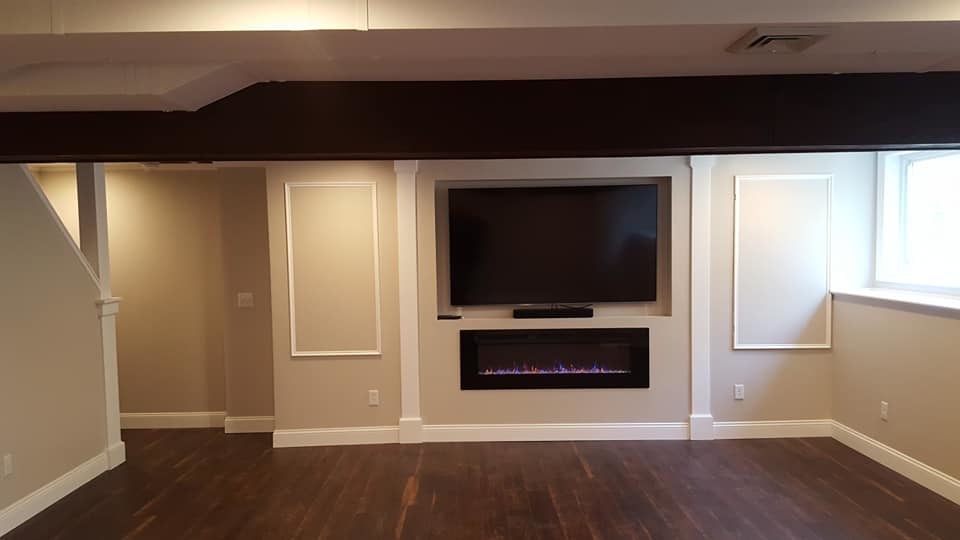 Design ideas for a medium sized classic look-out basement in Boston with beige walls, dark hardwood flooring, a ribbon fireplace, a plastered fireplace surround and brown floors.