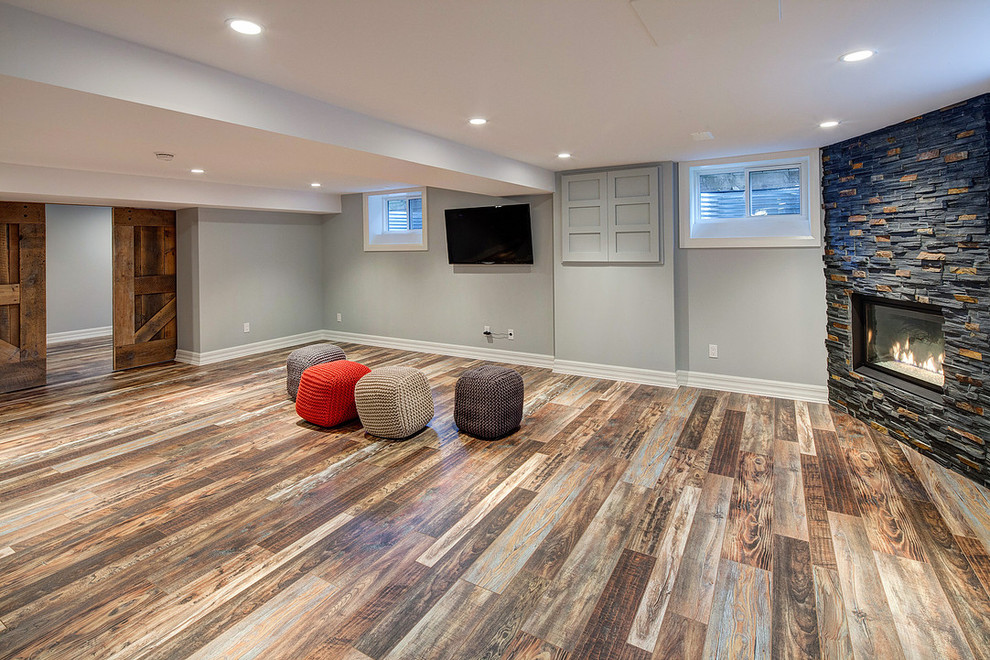 Inspiration for a large contemporary look-out dark wood floor basement remodel in Toronto with gray walls, a stone fireplace and a corner fireplace
