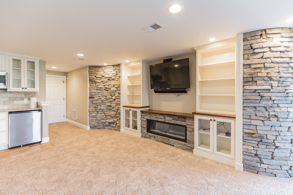 Photo of a large traditional walk-out basement in Philadelphia with beige walls, carpet, a ribbon fireplace, a stone fireplace surround and beige floors.