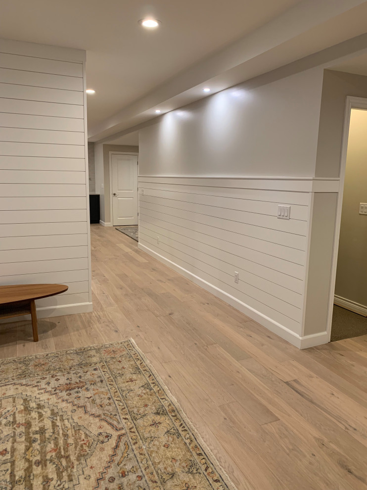 Design ideas for a medium sized scandinavian fully buried basement in Denver with beige walls, light hardwood flooring, beige floors, a drop ceiling and tongue and groove walls.