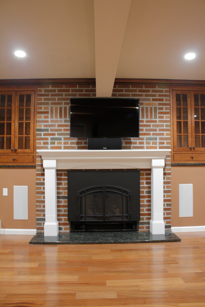 Example of a mid-sized classic walk-out medium tone wood floor basement design in New York with a standard fireplace and a brick fireplace