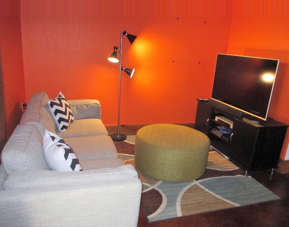 Example of a small mid-century modern walk-out concrete floor and brown floor basement design in Denver with orange walls, a wood stove and a stone fireplace