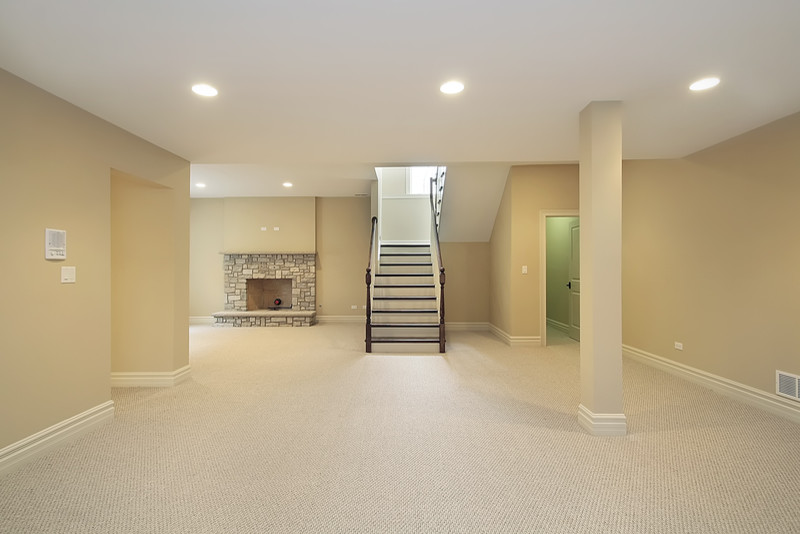 Example of a mid-sized classic underground carpeted basement design in New York with beige walls, a standard fireplace and a stone fireplace