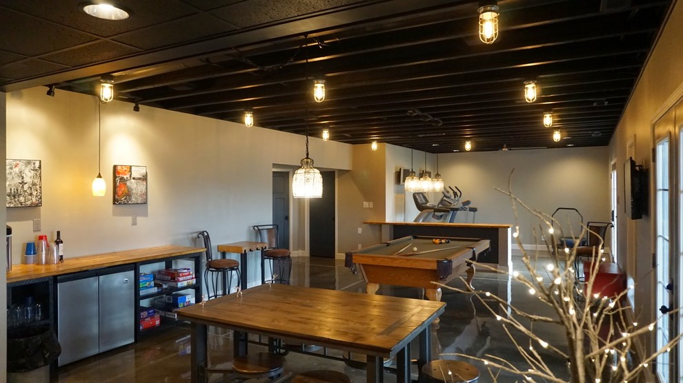 This is an example of a large modern walk-out basement in Louisville with grey walls, concrete flooring and no fireplace.