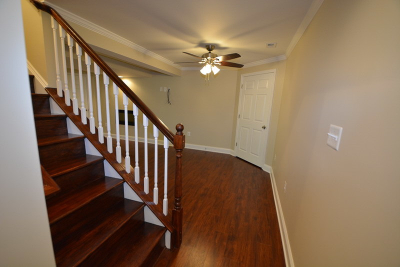 Example of a large classic walk-out dark wood floor basement design in Baltimore with beige walls and a ribbon fireplace
