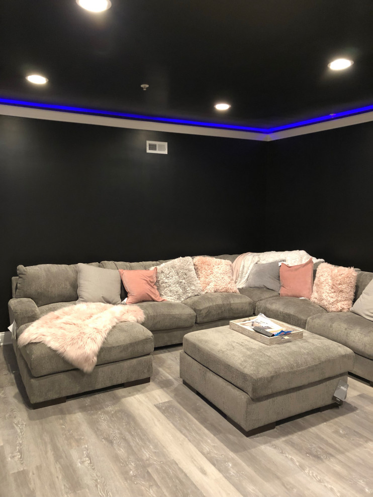 Home theater - large modern vinyl floor and brown floor home theater idea with black walls