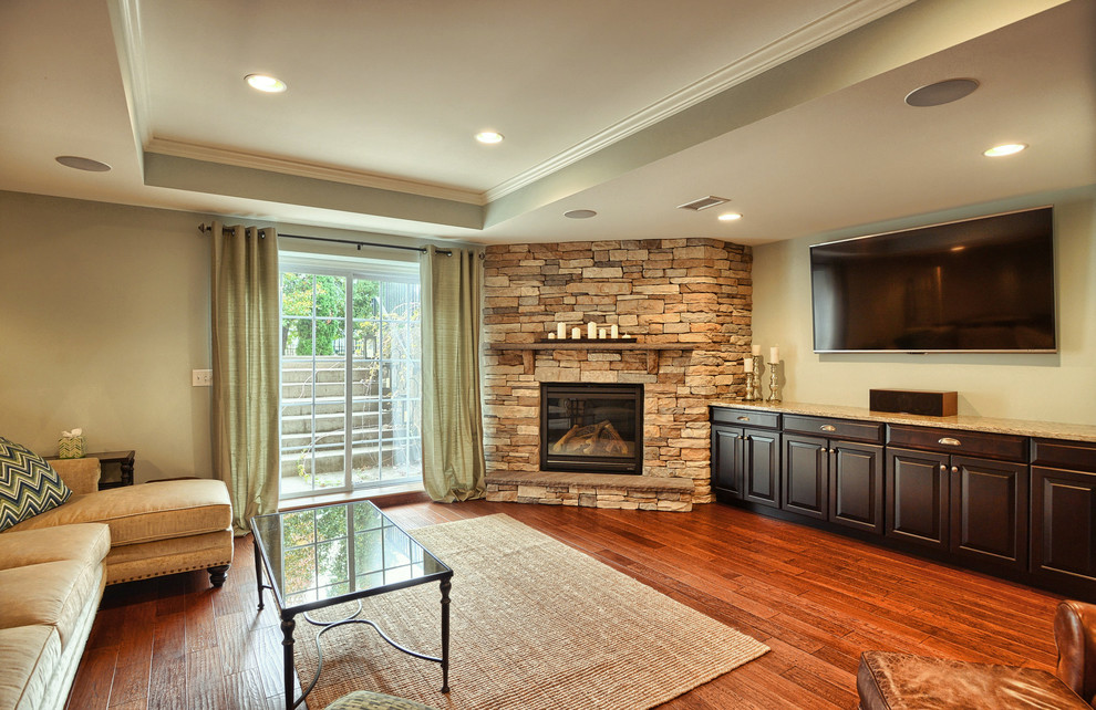 Example of a large classic walk-out medium tone wood floor basement design in Philadelphia with green walls, a standard fireplace and a stone fireplace