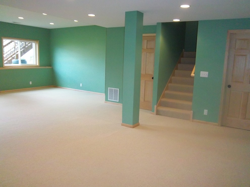 This is an example of a large bohemian look-out basement in Minneapolis with blue walls, carpet, no fireplace and beige floors.