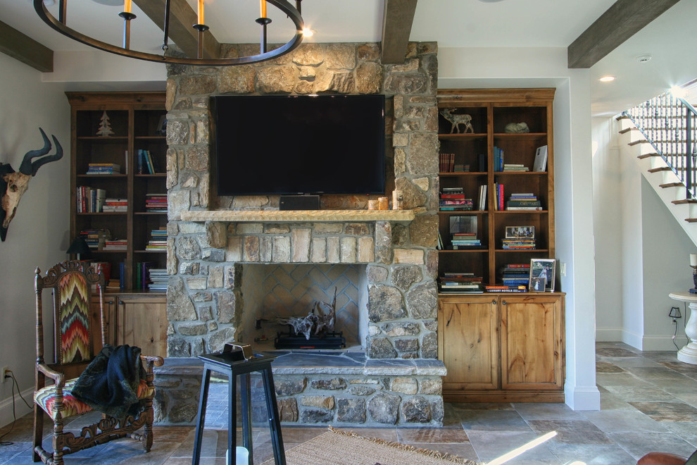 Idée de décoration pour un grand sous-sol chalet avec un manteau de cheminée en pierre, un mur blanc et une cheminée standard.