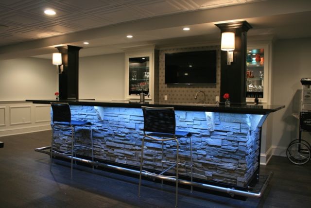 Foto di una grande taverna minimalista interrata con angolo bar, pareti bianche, parquet scuro, nessun camino, pavimento marrone, soffitto a cassettoni e boiserie