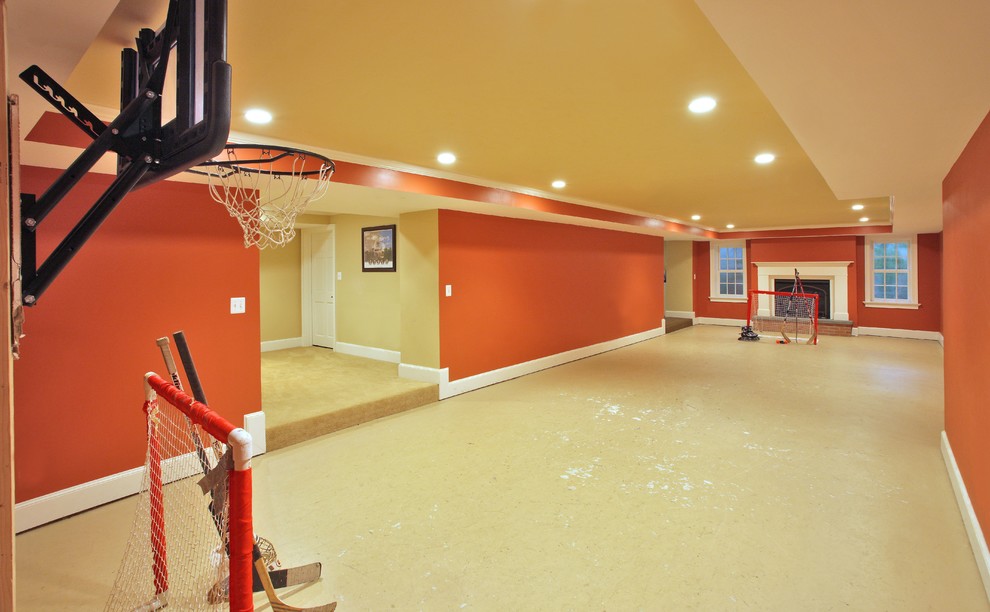 Cette image montre un grand sous-sol traditionnel avec un mur orange et sol en béton ciré.